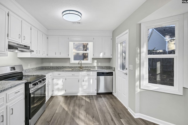 kitchen with dark wood-style flooring, appliances with stainless steel finishes, white cabinets, a sink, and under cabinet range hood