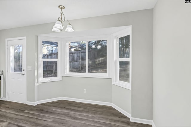 unfurnished dining area featuring baseboards, a chandelier, and dark wood-type flooring