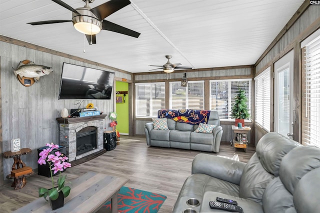 living area featuring a fireplace, wood finished floors, and a ceiling fan