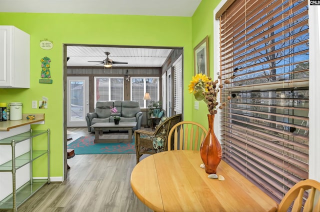 dining area featuring light wood-style flooring, baseboards, and a ceiling fan