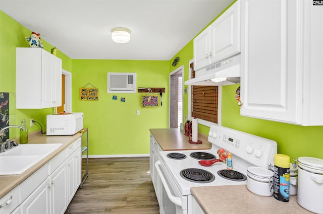 kitchen with white appliances, under cabinet range hood, white cabinets, and a sink