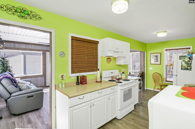 kitchen with under cabinet range hood, white appliances, light wood-style floors, white cabinets, and light countertops