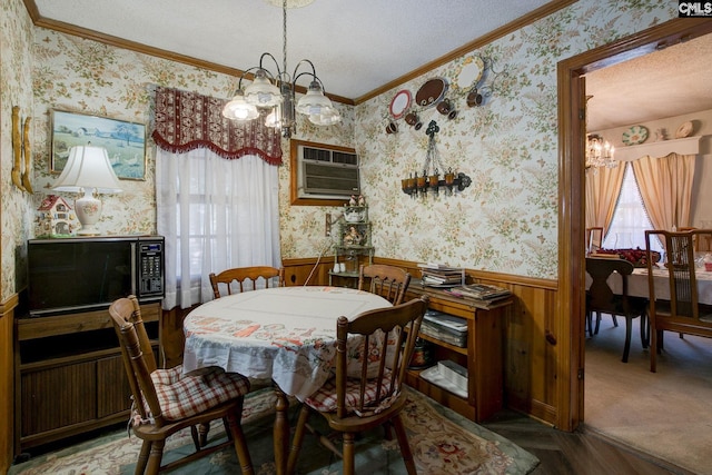 dining area featuring a notable chandelier, a wainscoted wall, a wall mounted AC, wallpapered walls, and crown molding