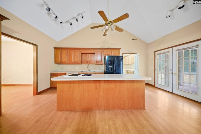 kitchen with french doors, light countertops, black refrigerator with ice dispenser, light wood-style floors, and a sink