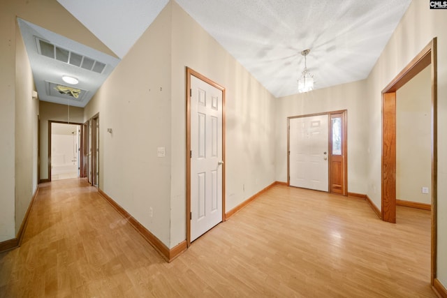 entryway featuring visible vents, a textured ceiling, light wood-style flooring, and baseboards