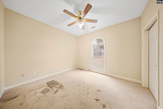 unfurnished bedroom featuring a textured ceiling, ceiling fan, visible vents, baseboards, and carpet