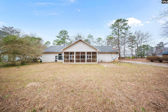 back of property with a sunroom and a lawn