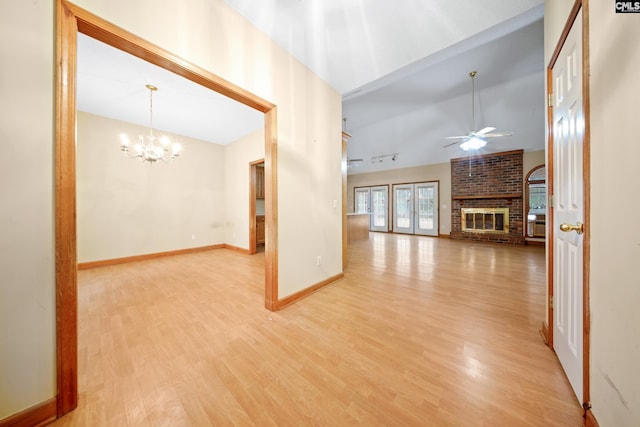 unfurnished living room with a fireplace, lofted ceiling, light wood-style floors, baseboards, and ceiling fan with notable chandelier