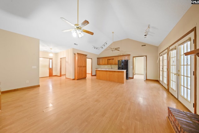 unfurnished living room with lofted ceiling, light wood finished floors, a ceiling fan, and french doors