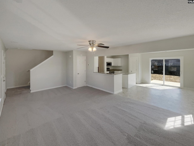 unfurnished living room with light colored carpet, ceiling fan, baseboards, and stairs