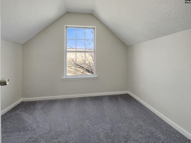 additional living space with vaulted ceiling, a textured ceiling, and baseboards