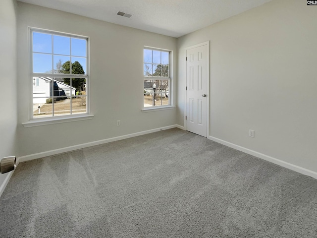 spare room with carpet floors, visible vents, and baseboards