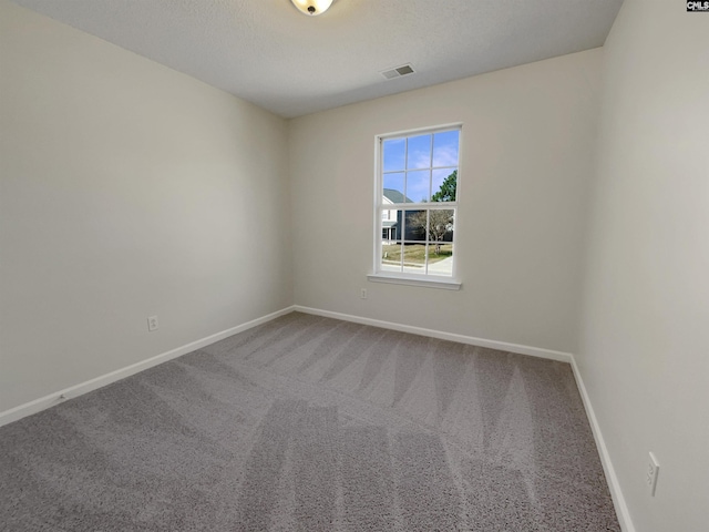 empty room featuring a textured ceiling, carpet floors, visible vents, and baseboards