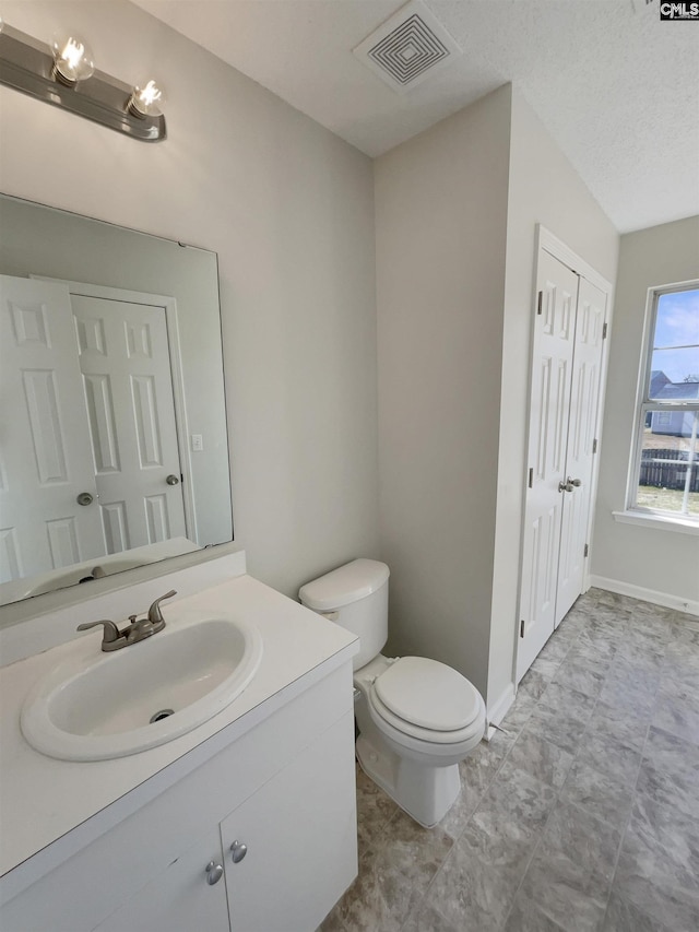 bathroom featuring toilet, vanity, visible vents, and baseboards