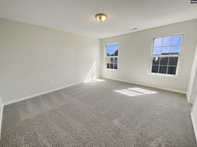 carpeted empty room with visible vents, a textured ceiling, and baseboards