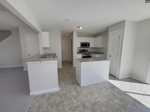 kitchen with stainless steel appliances, white cabinetry, a peninsula, and light stone countertops