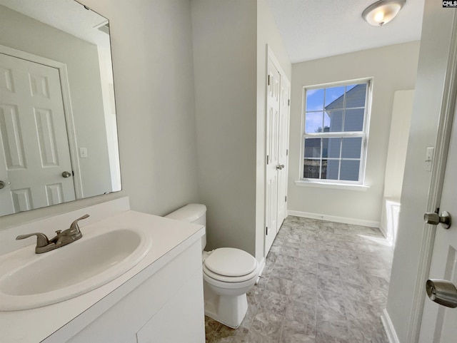 bathroom featuring baseboards, vanity, and toilet