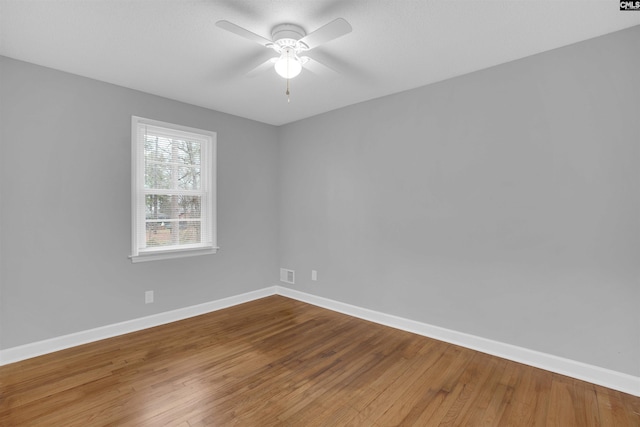 unfurnished room featuring visible vents, wood finished floors, a ceiling fan, and baseboards