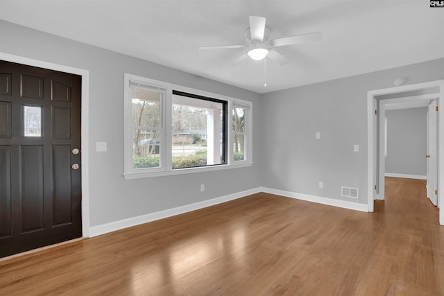 entryway featuring a ceiling fan, wood finished floors, visible vents, and baseboards