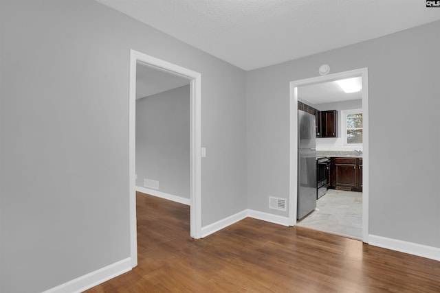 empty room with light wood finished floors, baseboards, and visible vents