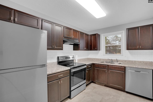 kitchen with under cabinet range hood, stainless steel appliances, a sink, and light countertops