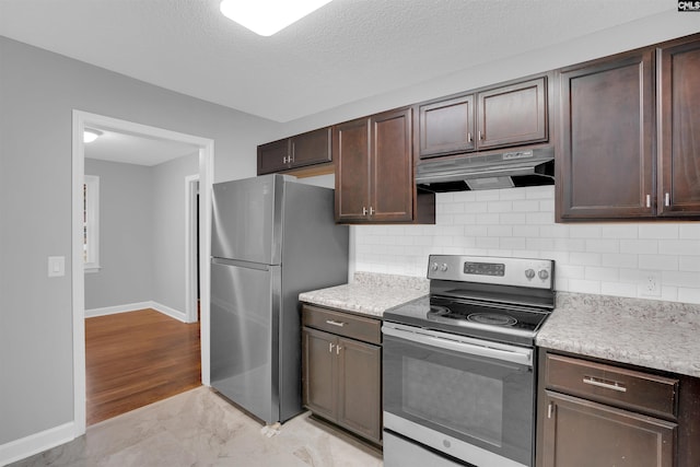 kitchen with appliances with stainless steel finishes, a textured ceiling, dark brown cabinets, under cabinet range hood, and backsplash