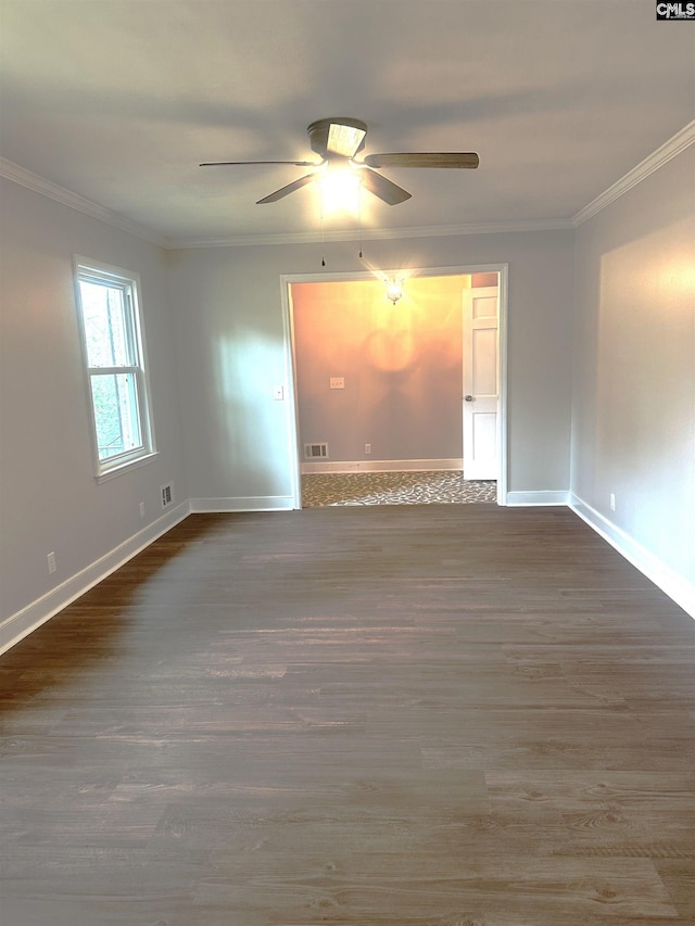 spare room featuring visible vents, crown molding, baseboards, and wood finished floors