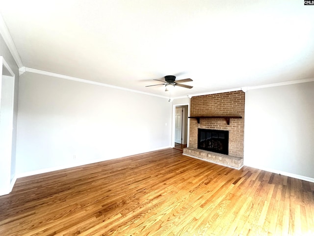 unfurnished living room featuring a brick fireplace, wood finished floors, and crown molding