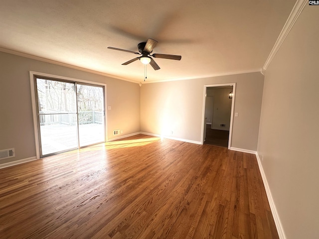 spare room with baseboards, visible vents, a ceiling fan, ornamental molding, and wood finished floors