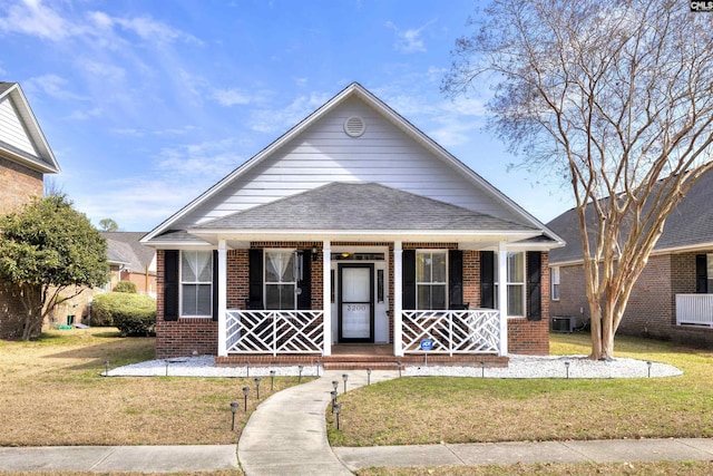 bungalow-style home with a porch, brick siding, a shingled roof, and a front lawn