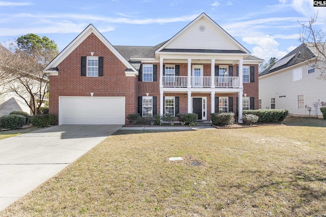 greek revival house featuring a balcony, driveway, a front lawn, and brick siding