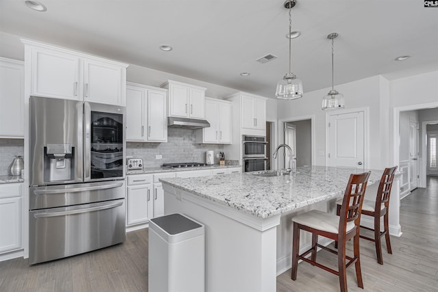 kitchen with stainless steel appliances, visible vents, under cabinet range hood, and decorative backsplash