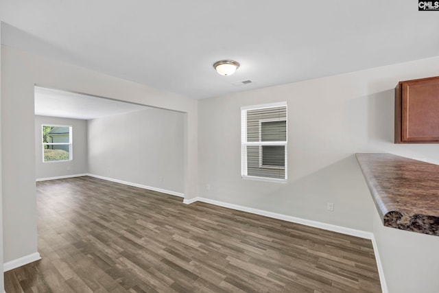 unfurnished room featuring visible vents, dark wood finished floors, and baseboards