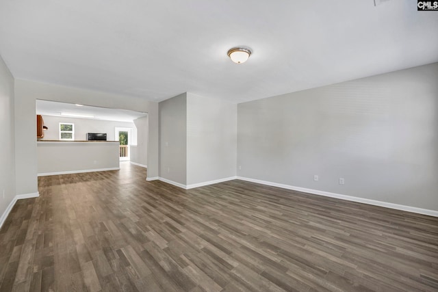 unfurnished living room featuring baseboards and dark wood-type flooring