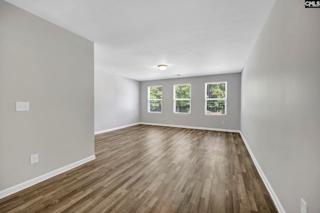 spare room with dark wood-type flooring and baseboards