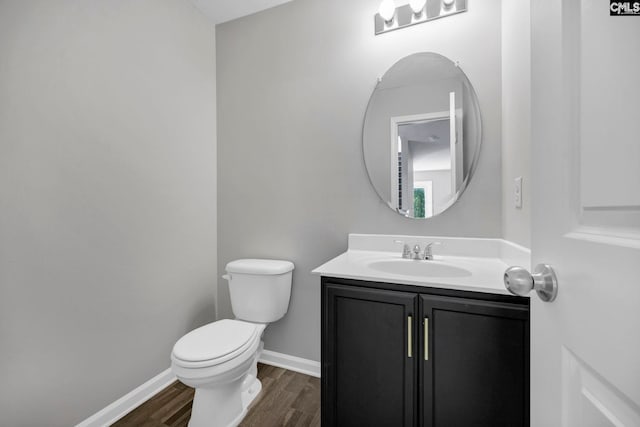 bathroom featuring toilet, baseboards, wood finished floors, and vanity