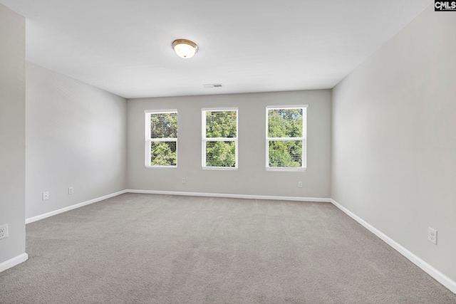 empty room with carpet floors, visible vents, and baseboards