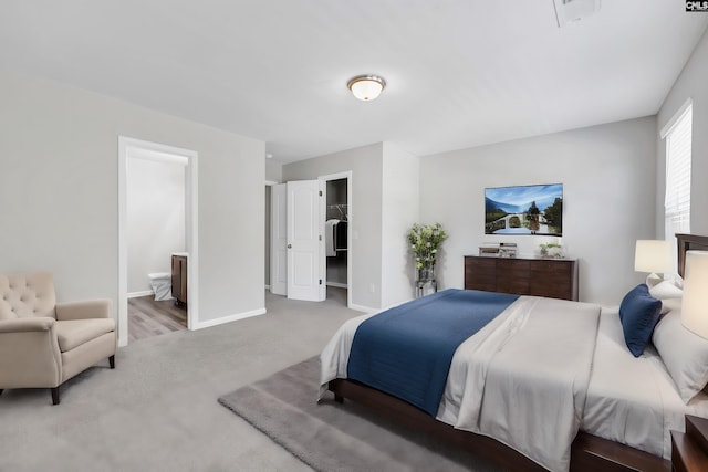 bedroom featuring visible vents, a spacious closet, light carpet, connected bathroom, and baseboards