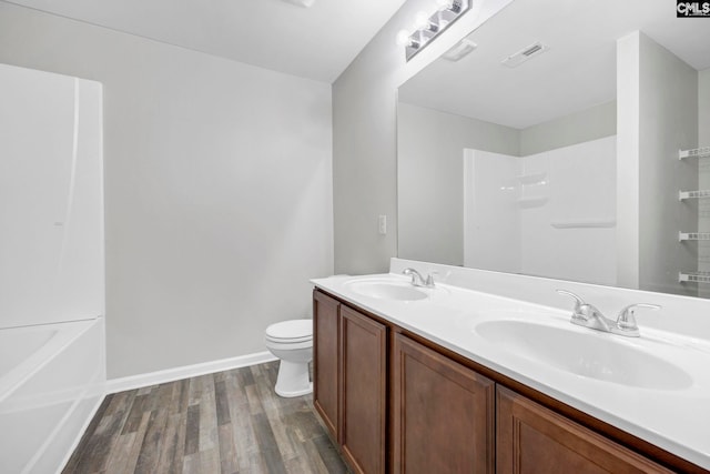 full bathroom with visible vents, a sink, toilet, and wood finished floors