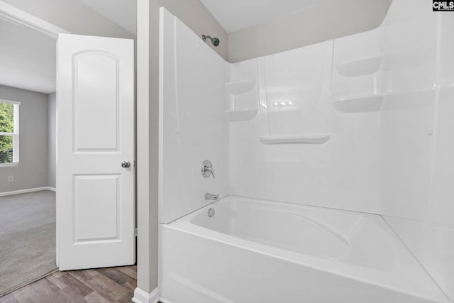 full bathroom with washtub / shower combination, baseboards, and wood finished floors