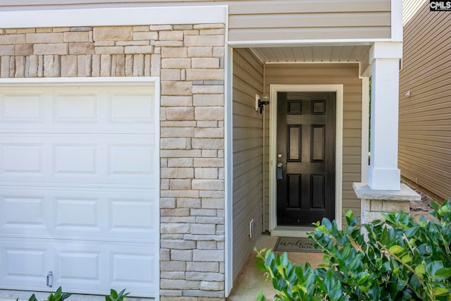 view of exterior entry with a garage and stone siding