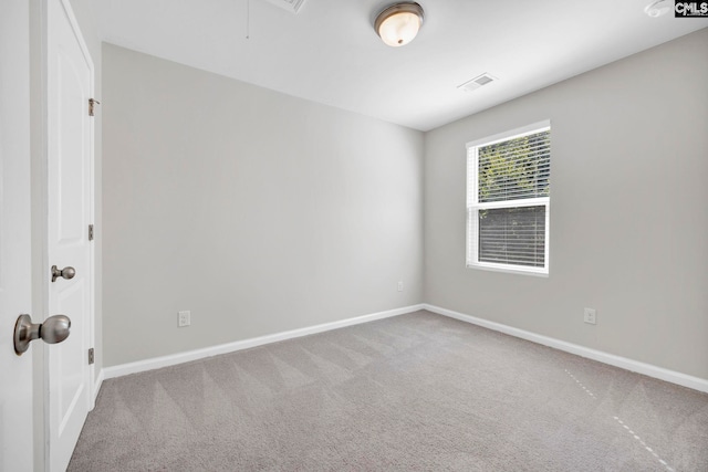 carpeted empty room featuring attic access, visible vents, and baseboards