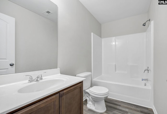 bathroom with visible vents, toilet, wood finished floors, vanity, and washtub / shower combination