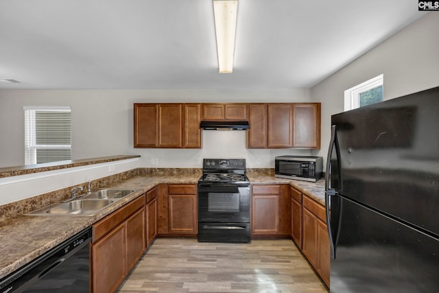 kitchen featuring black appliances, light wood-style floors, a sink, and under cabinet range hood