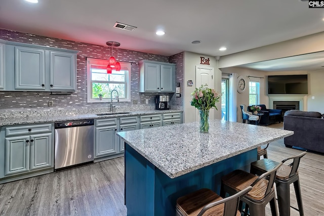 kitchen featuring a sink, visible vents, open floor plan, stainless steel dishwasher, and a kitchen bar