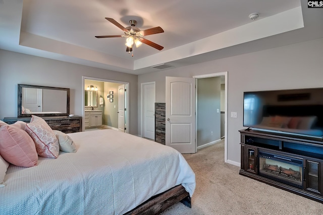 carpeted bedroom featuring ensuite bathroom, ceiling fan, visible vents, baseboards, and a tray ceiling