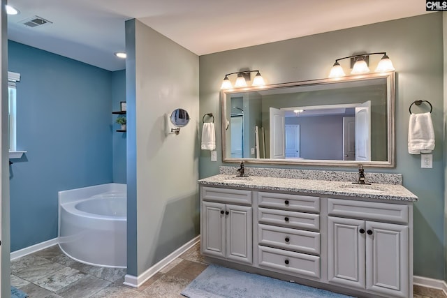 bathroom featuring double vanity, visible vents, baseboards, and a sink