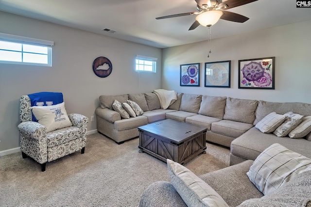 living room with a ceiling fan, visible vents, light carpet, and baseboards