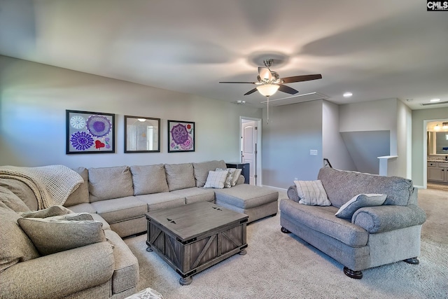 living area with light carpet, ceiling fan, attic access, and baseboards