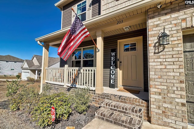 doorway to property featuring covered porch and brick siding